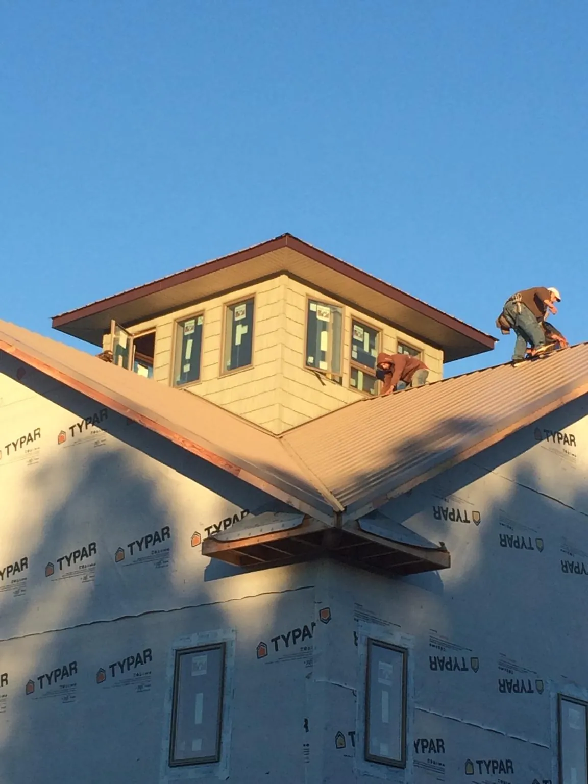 Roofers working around a rooftop cupola on a new metal roof at sunset — Roof Waterproofing in Etna by Roofing Brothers